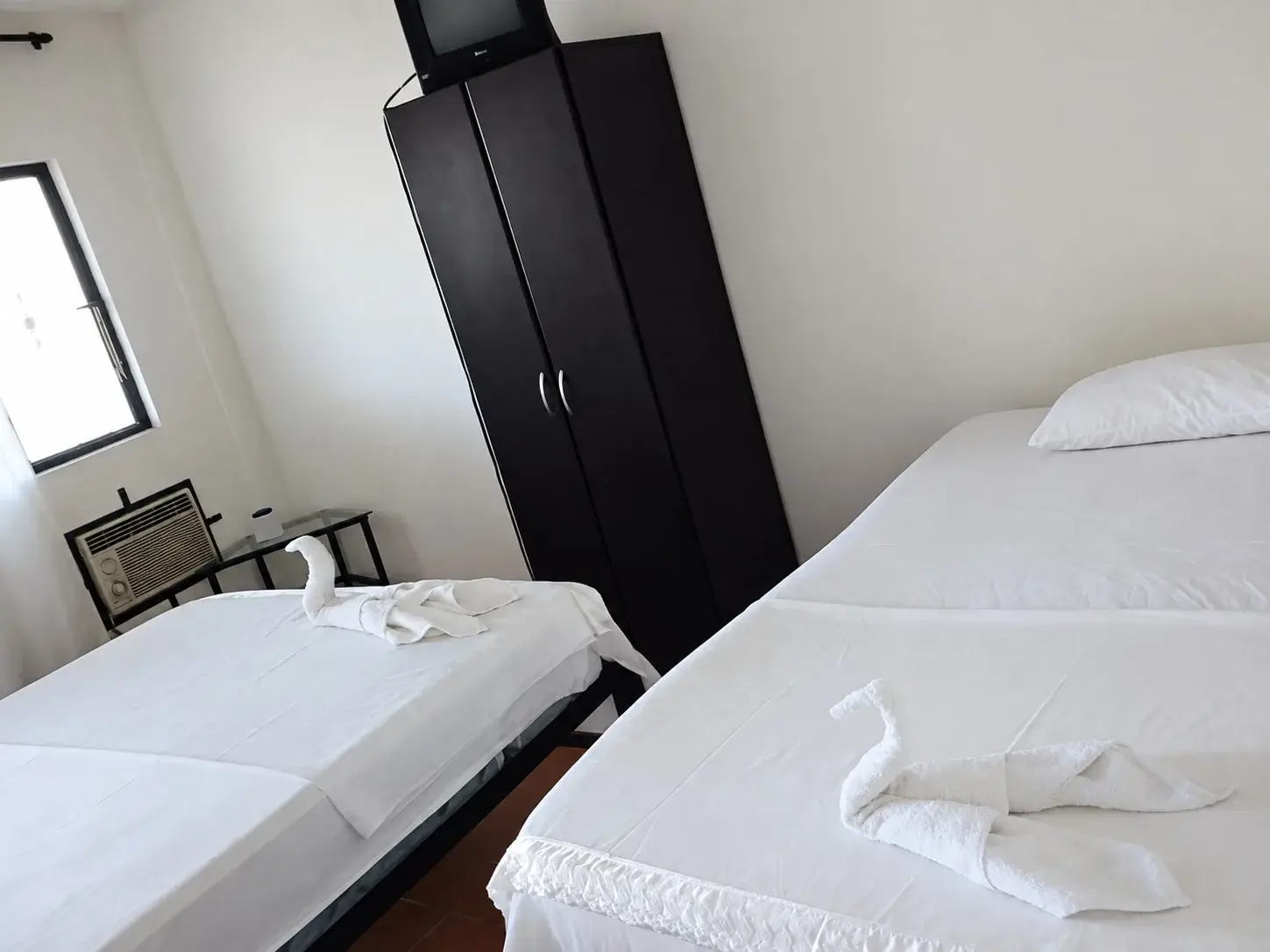 Habitación con dos camas tendidas, clóset y aire acondicionado del hospedaje en La Primavera, Vichada.