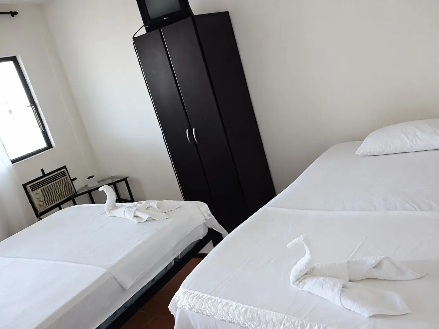 Habitación con dos camas tendidas, clóset y aire acondicionado.