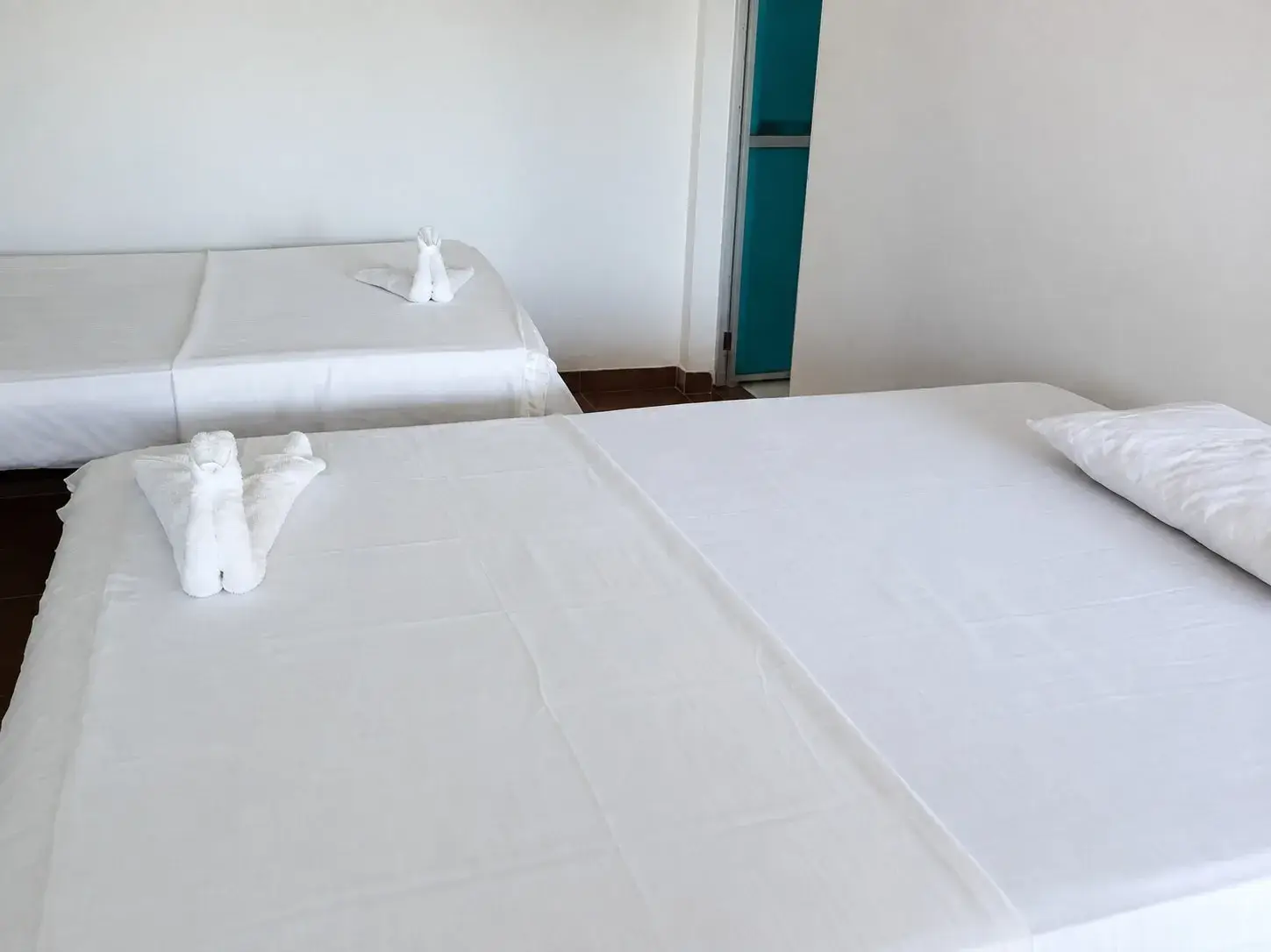 Habitación con dos camas tendidas y toallas dobladas.