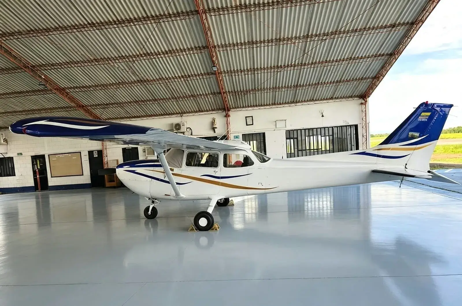 Avioneta blanca y azul dentro de un hangar.