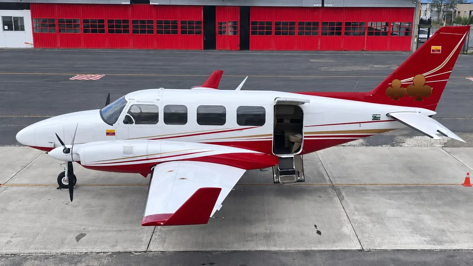 Avioneta bimotor blanca y roja en plataforma.