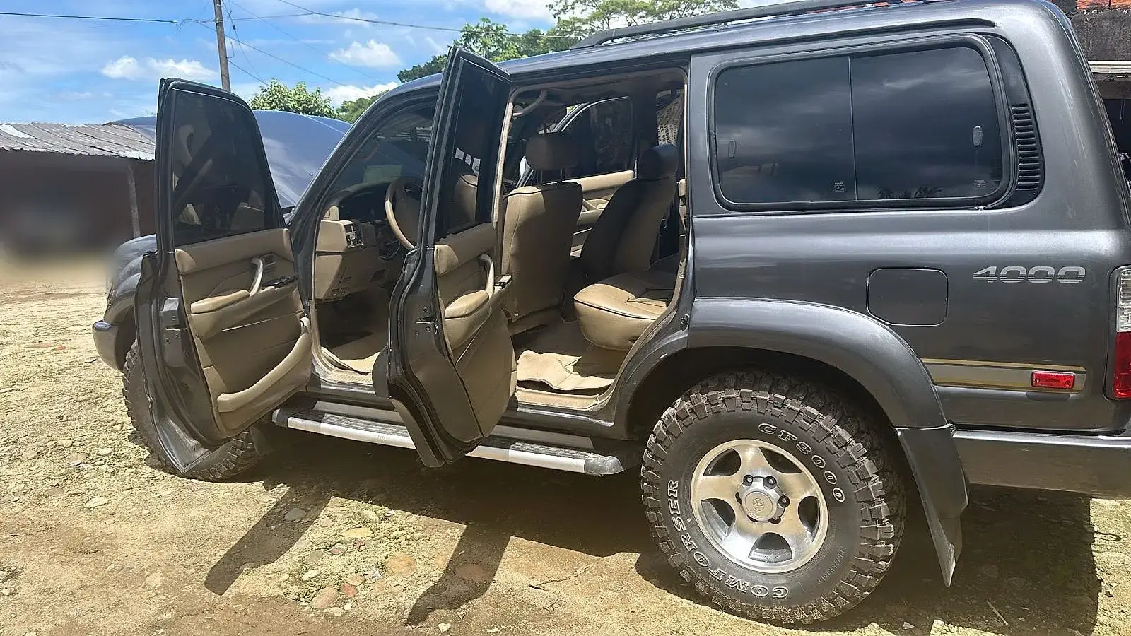 Camioneta 4x4 con las puertas abiertas en un patio de tierra.